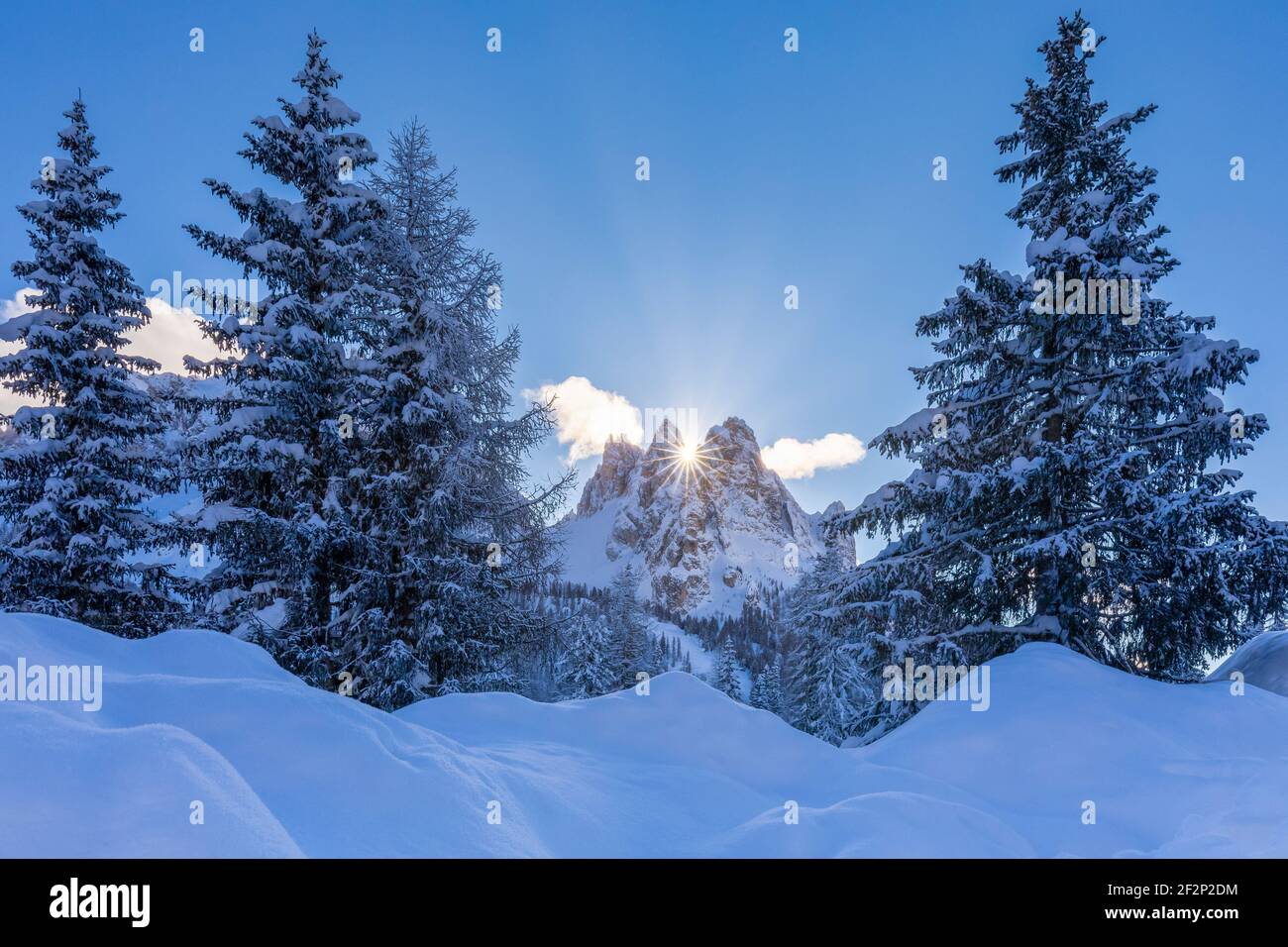 Italien, Venetien, Provinz Belluno, Auronzo di Cadore. Die Sonne geht zwischen Cadin della Neve und Cadin di Misurina in einer Winterlandschaft mit schneebedeckten Tannen, Cadini di Misurina, Dolomiten auf Stockfoto