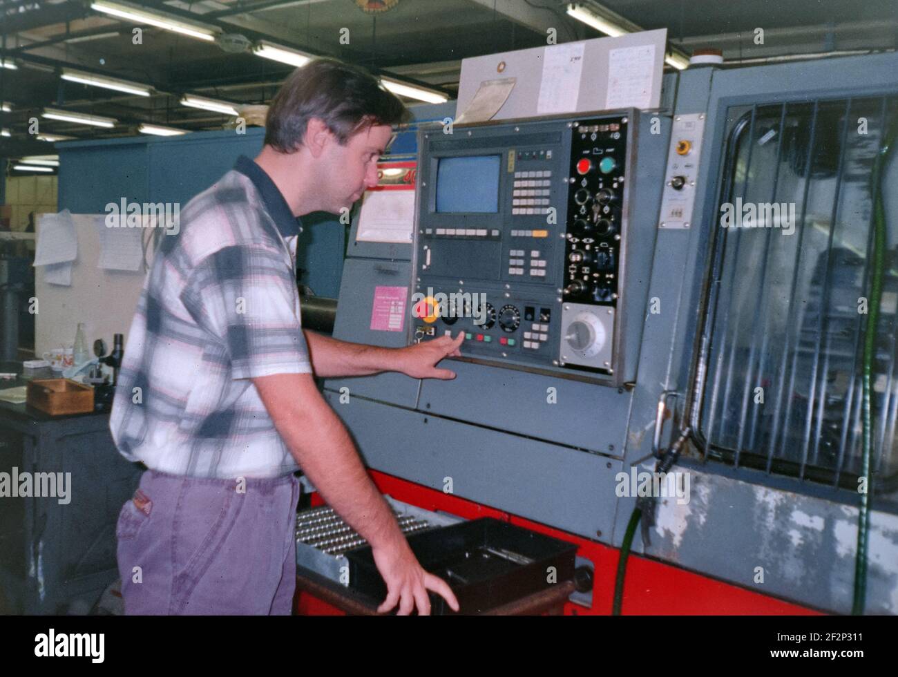 Ein Mann betreibt eine numerische Steuermaschine in einer Fabrik, Archivfoto, 90s. Tschechische republik. Stockfoto