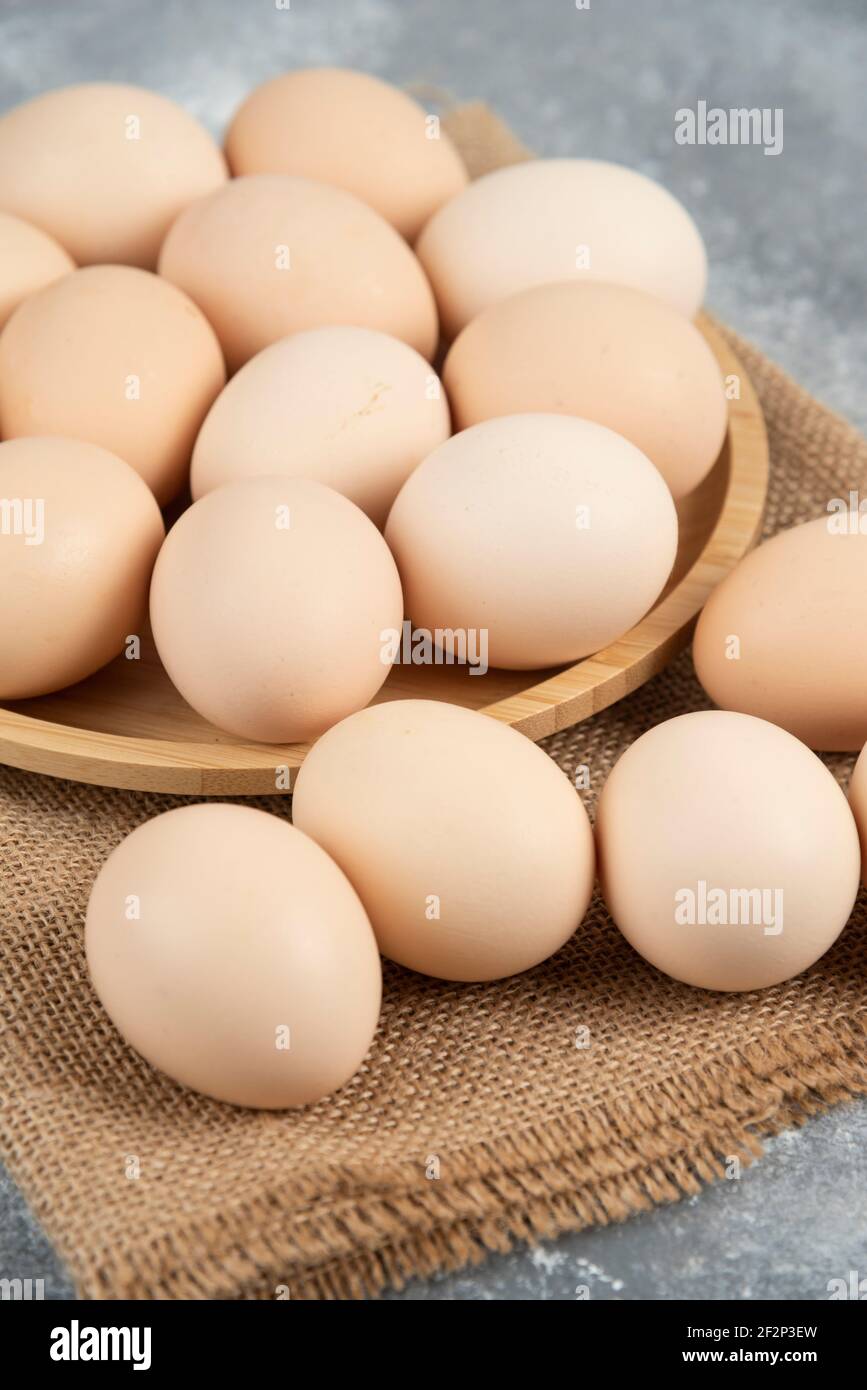 Holzplatte aus Bio-ungekochten Eiern auf Marmoroberfläche Stockfoto