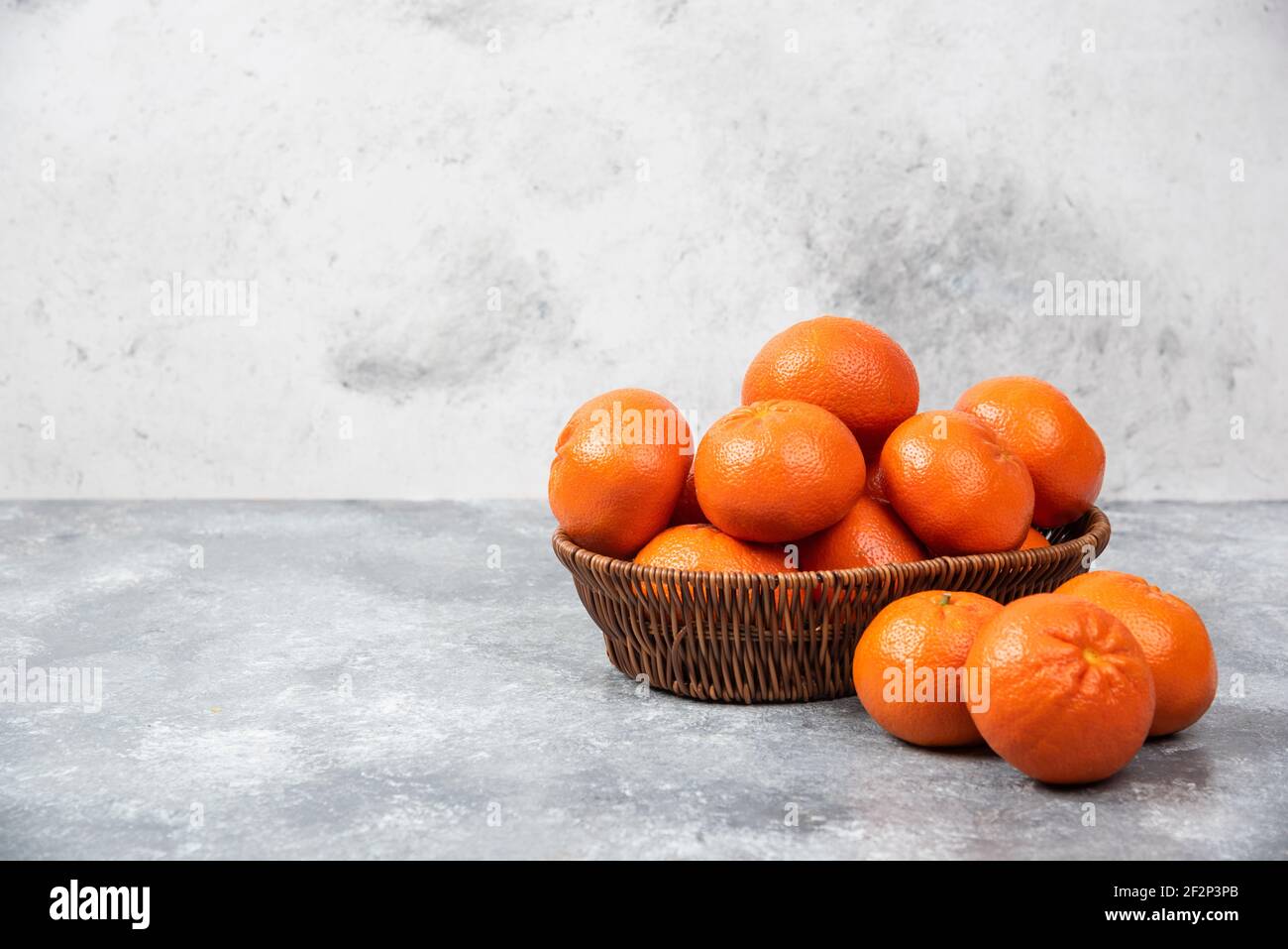Eine Korbbox voller saftiger Orangenfrüchte auf Stein Hintergrund Stockfoto