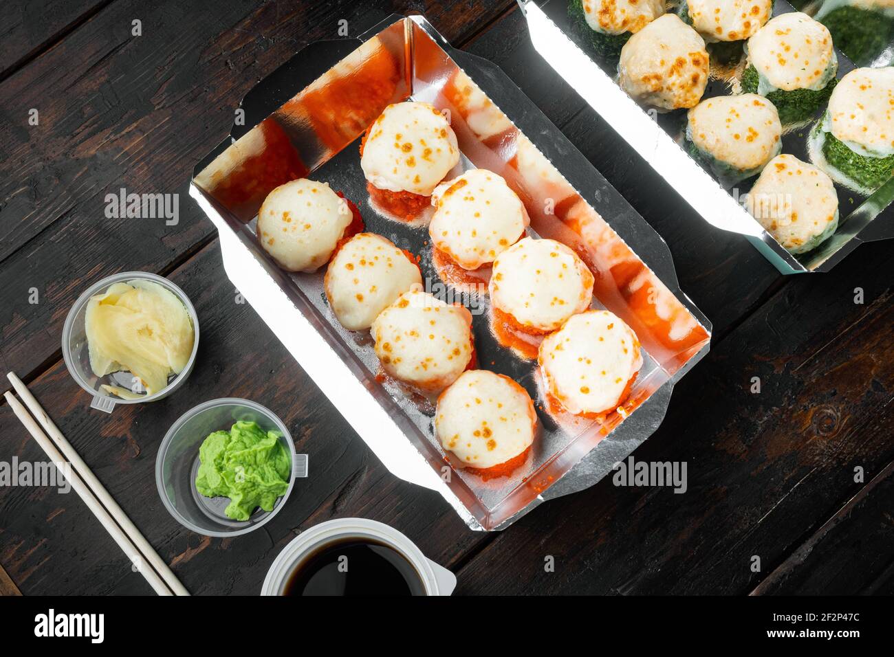 Sushi-Rollen im Container-Set zum Mitnehmen, auf altem dunklen Holztischhintergrund Stockfoto