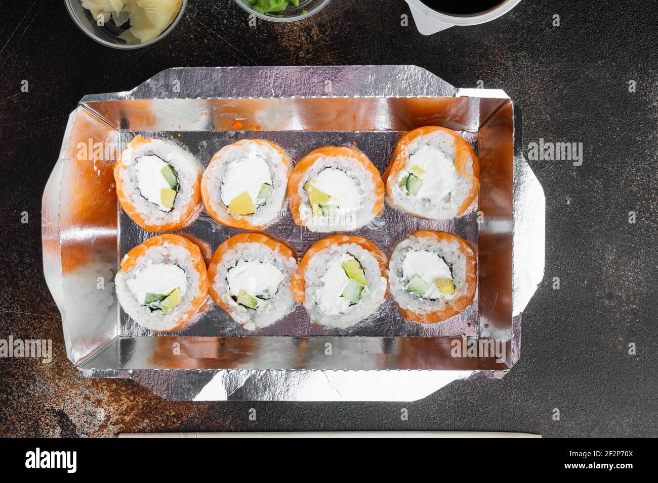 Sushi-Rollen im Takeaway-Container-Set, auf altem dunklen rustikalen Hintergrund, Draufsicht flach liegend, mit Copyspace und Platz für Text Stockfoto