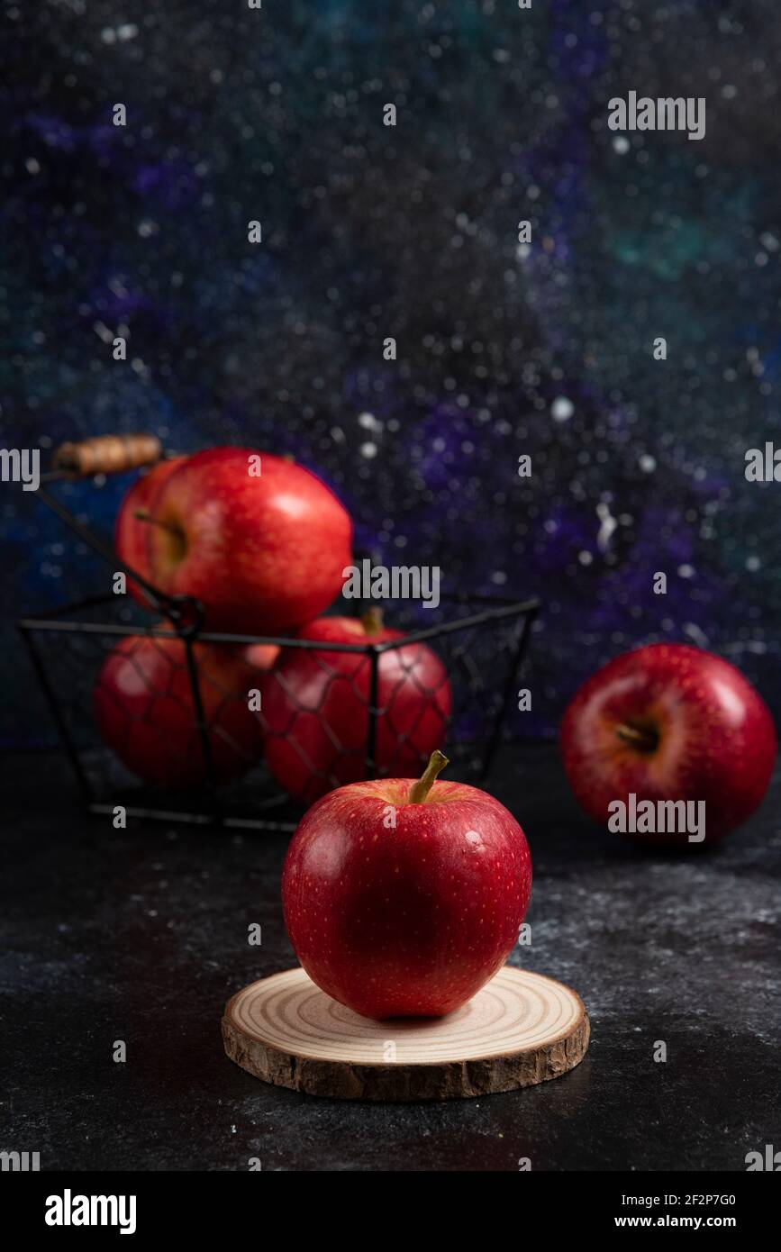 Rote ganze Äpfel in Metallkorb auf dunklem Hintergrund Stockfoto