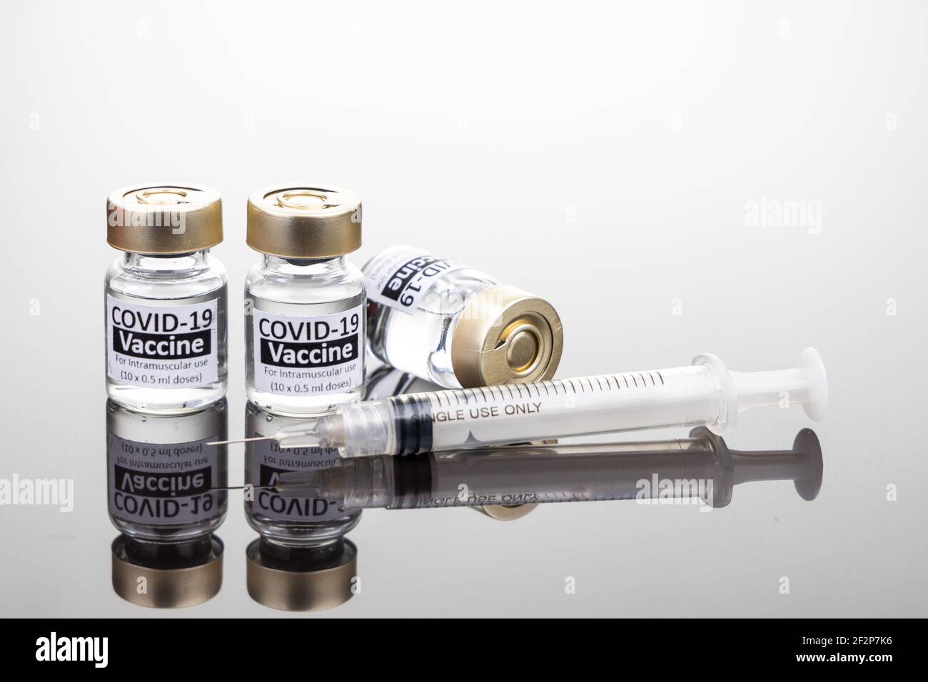 Covid-19 Impfstofffläschchen mit Spritzenkonzept auf reflektierender Oberfläche Stockfoto
