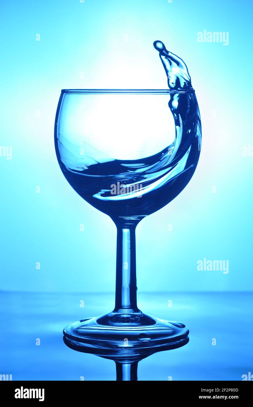 Glas Wasser mit Spritzer auf blauem Hintergrund. Getränke mit Spritzwasser. Stockfoto
