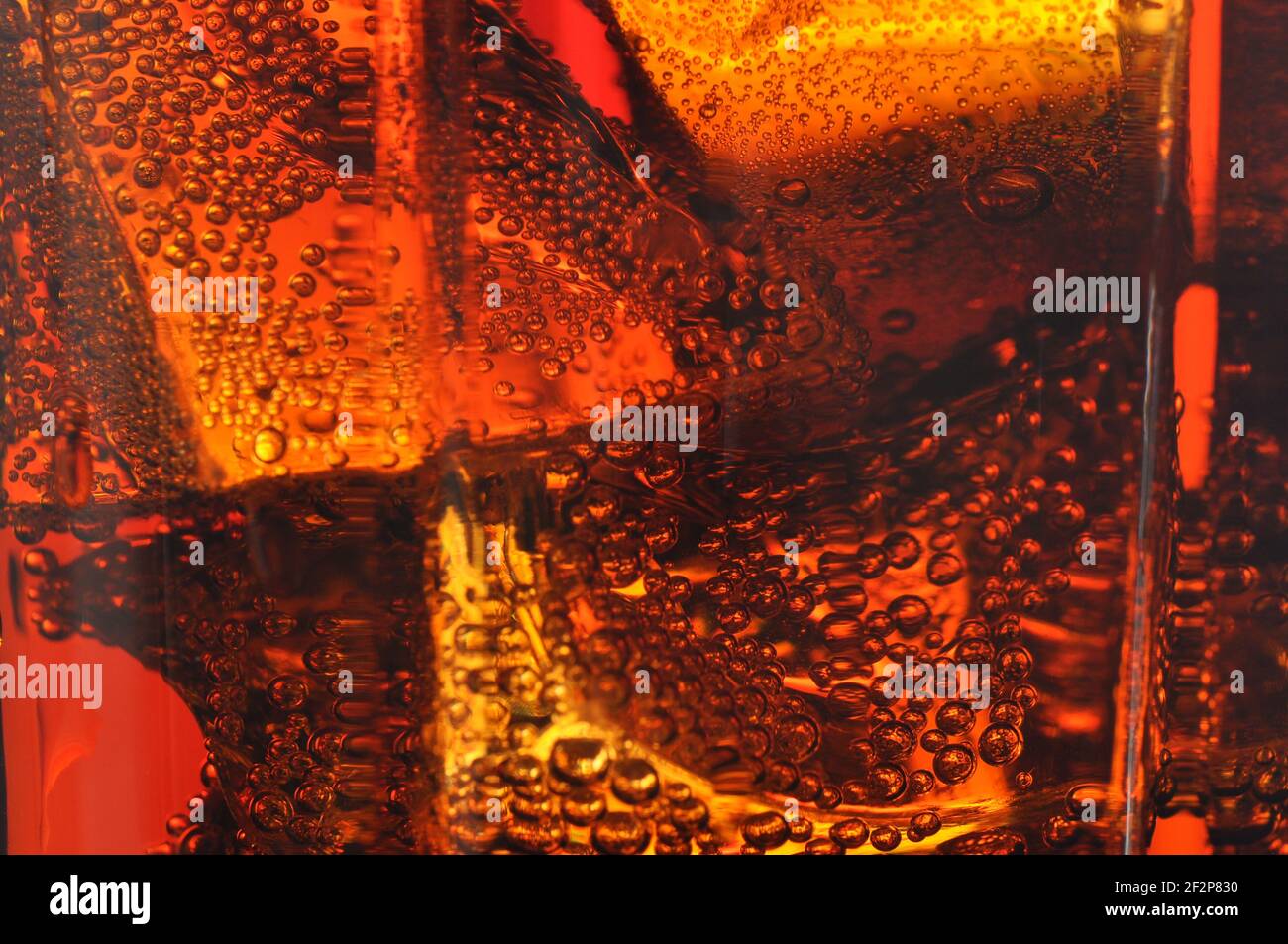 Cola im Glas mit Eis und Gasblasen. Makrofoto. Stockfoto