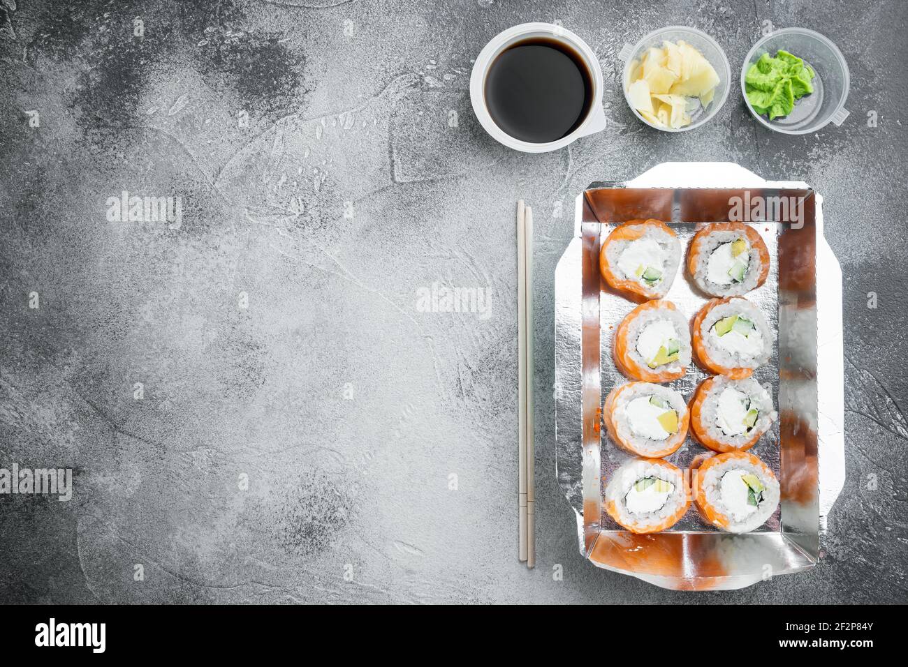 Set von Sushi-Rollen in Lieferung Food-Box-Set, auf grauem Stein Hintergrund, Draufsicht flach legen, mit Copyspace und Platz für Text Stockfoto