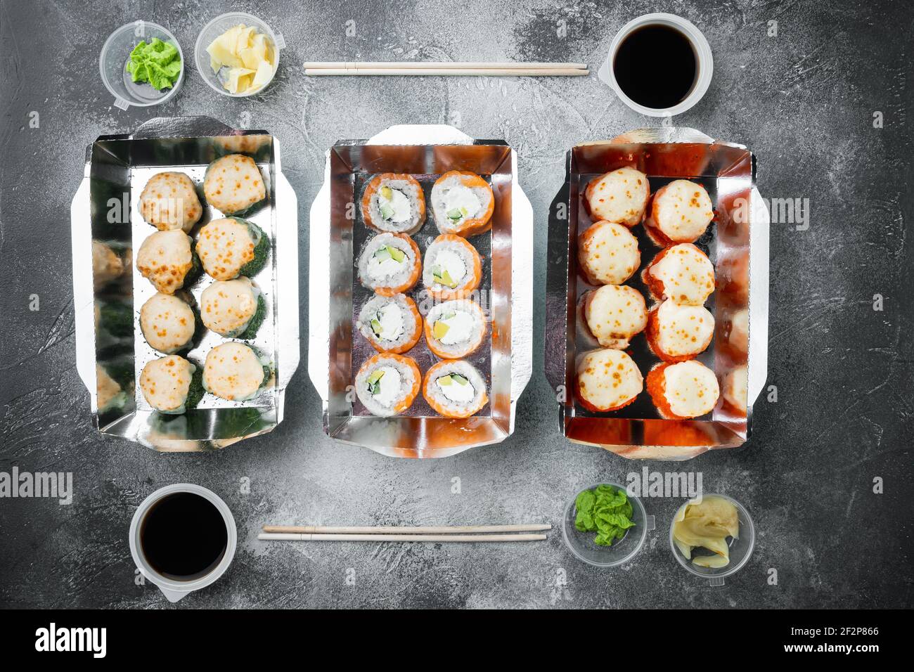 Japanisches Speisekonzept. Catering, verschiedene Arten von Sushi philadelphia Brötchen und gebackene Garnelen Brötchen Set, auf grauem Stein Hintergrund, Draufsicht flach legen Stockfoto