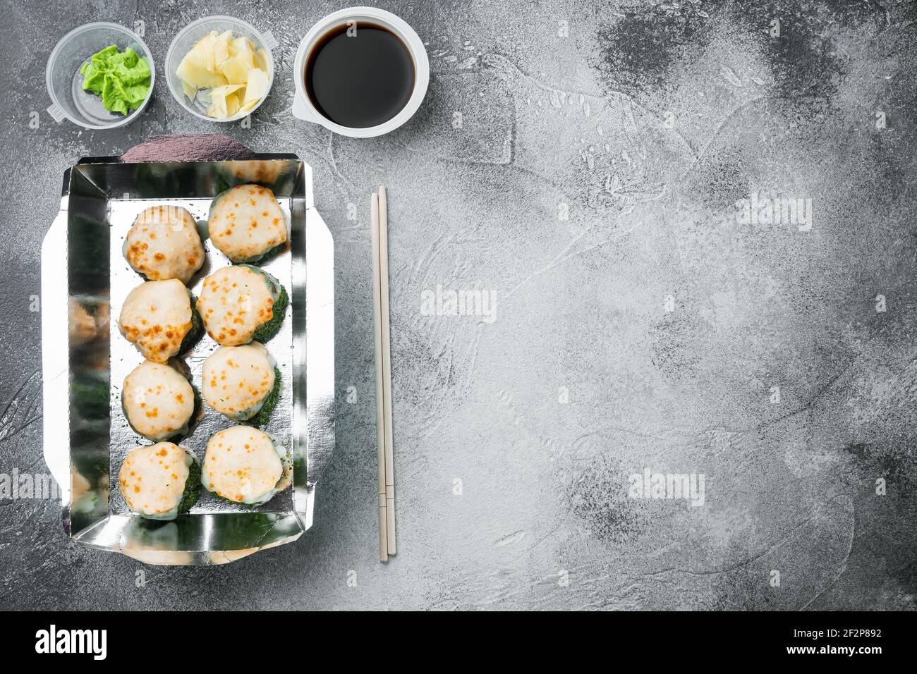 Vielfalt an verschiedenen Sushi und Brötchen, Lachs und Thunfisch im Lieferlebensmittelkonzept Set, auf grauem Steinhintergrund, Draufsicht flach liegend, mit Copyspace A Stockfoto