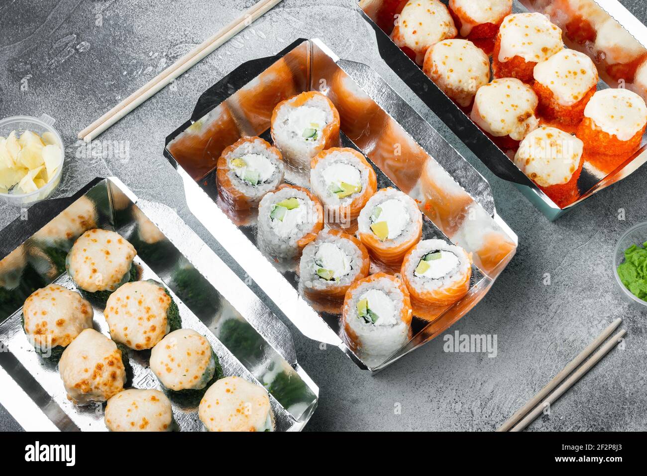 Set von Sushi-Rollen in Lieferung Food-Box-Set, auf grauem Stein Hintergrund Stockfoto
