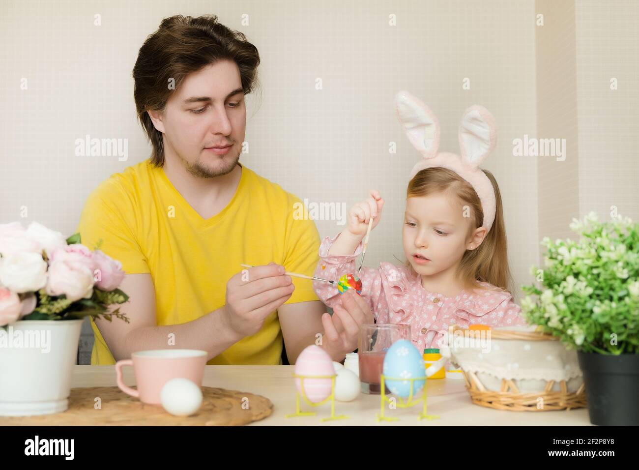 Ostern, Familie, Urlaub und Kinder Konzept. Vater und Tochter malen Eier. Glückliche Familie bereitet sich auf Ostern vor Stockfoto