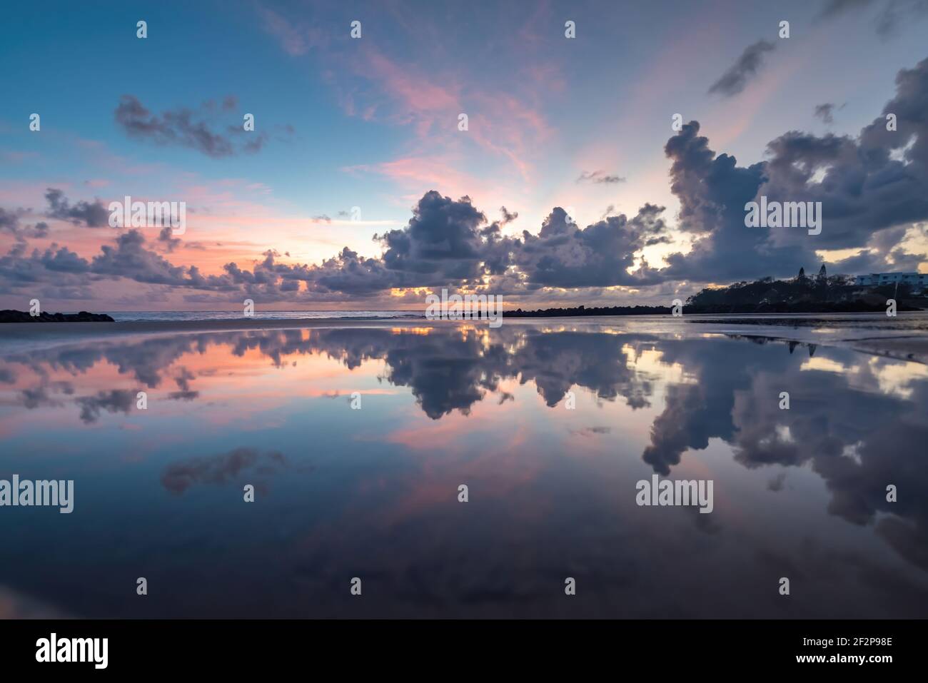 Die Morgenwolken reflektieren sich am Strand. Stockfoto