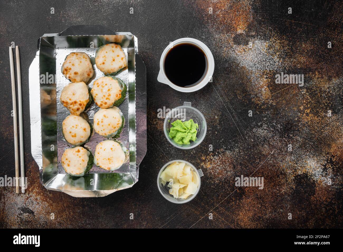 Sushi-Rollen im Takeaway-Container-Set, auf altem dunklen rustikalen Hintergrund, Draufsicht flach liegend, mit Copyspace und Platz für Text Stockfoto