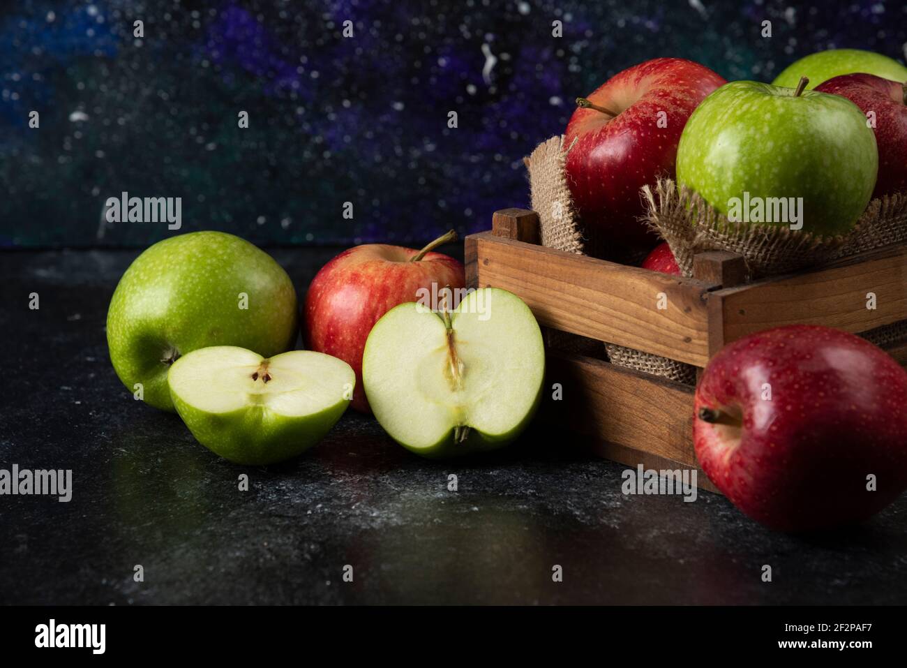 Holzkiste mit frischen Bio-Äpfeln auf schwarzem Hintergrund Stockfoto