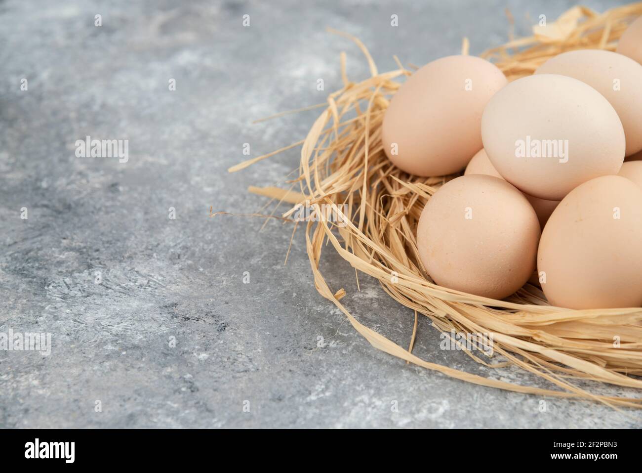 Haufen roher Eier mit Vogelnest auf Marmoroberfläche Stockfoto