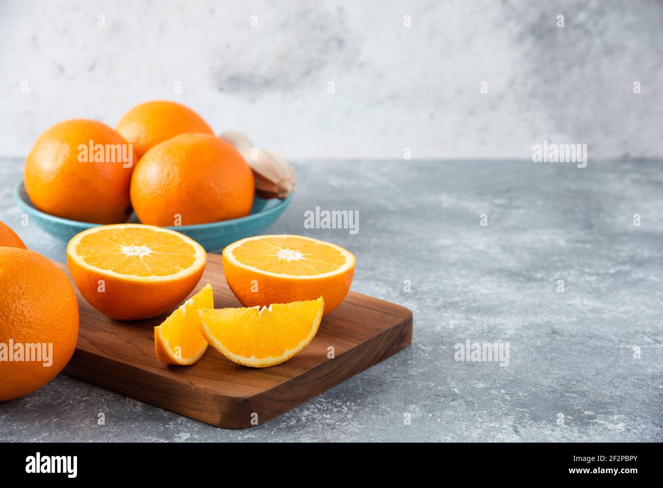 In Scheiben geschnittene Orangenfrüchte mit ganzen Orangen auf einem Holzbrett Stockfoto