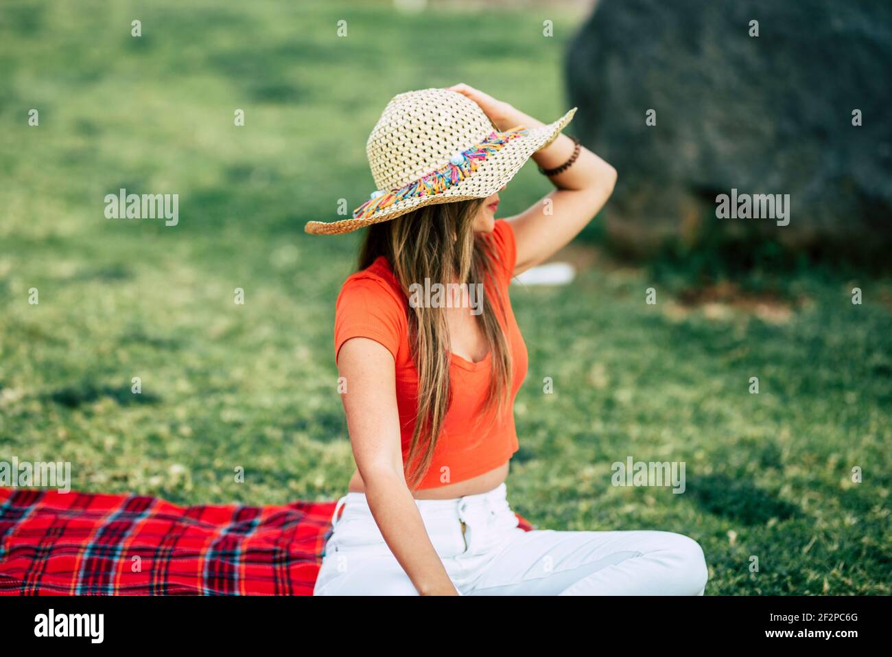 Mode junge Dame von hinten betrachtet entspannen und genießen Sie die blick auf den ozean sitzend auf dem Feld Gras mit Tasse Kaffee - Konzept der touristischen und Frühling Sommerferien Urlaub Aktivitäten im Freien Stockfoto