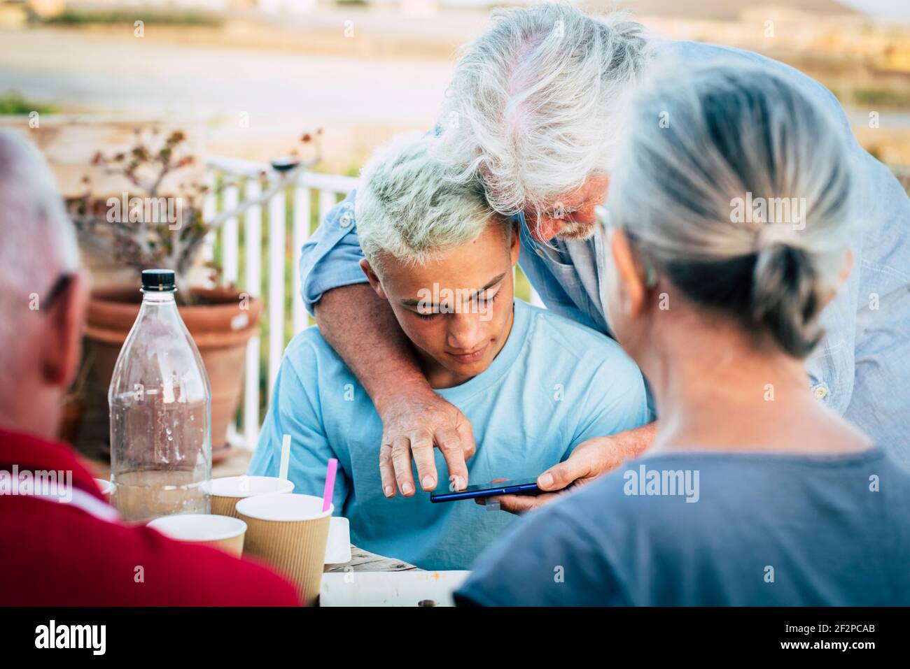 Großvater erklären ihr Enkel Teenager Jungen Smartphone-Nutzung - Gruppe von Menschen zusammen im Freien genießen Freundschaft und Familie Konzept Freizeitgestaltung Stockfoto