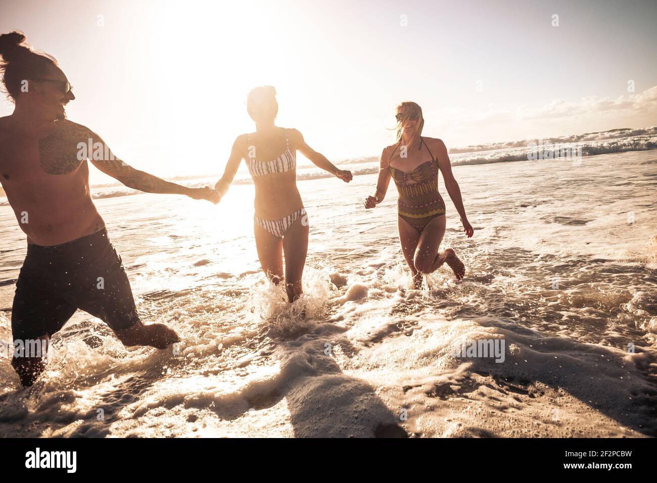 Drei junge Menschen genießen Sommerferien in Freundschaftsspielen Mit Meereswellen am Strand - Konzept des Touristen Freunde genießen die Meer Freizeitaktivitäten im Freien Stockfoto