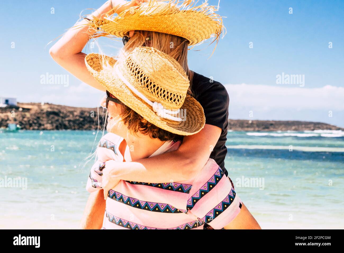 Tourismus und glückliche Menschen genießen im Freien Sommerurlaub am Strand mit blauem Meer und Himmel im Hintergrund. Junger Mann tragen Frau und Spaß haben Liebe und Freundschaft zusammen Stockfoto