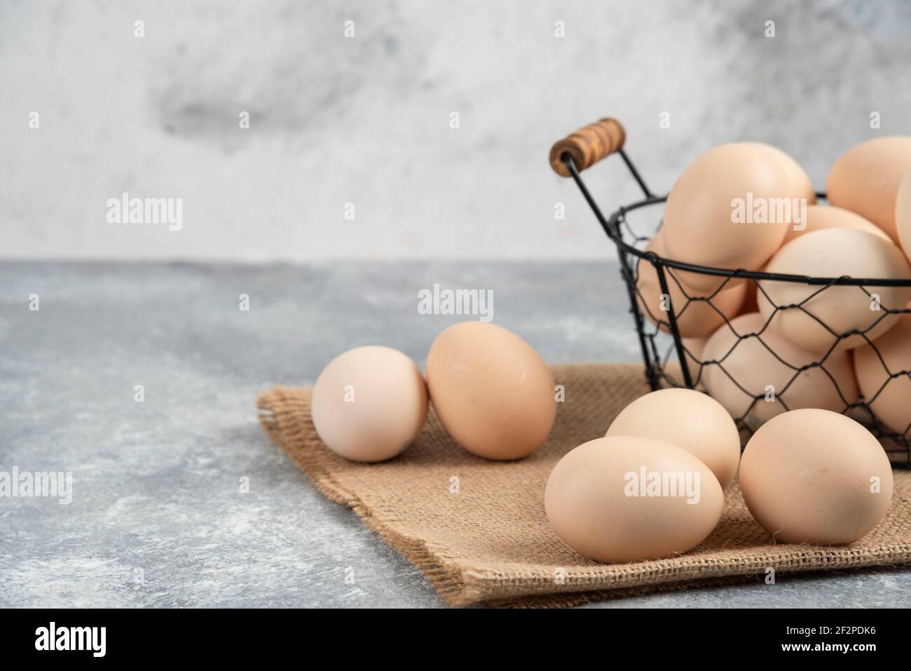 Korbkorb mit rohen Bio-Eiern auf Marmorboden Stockfoto