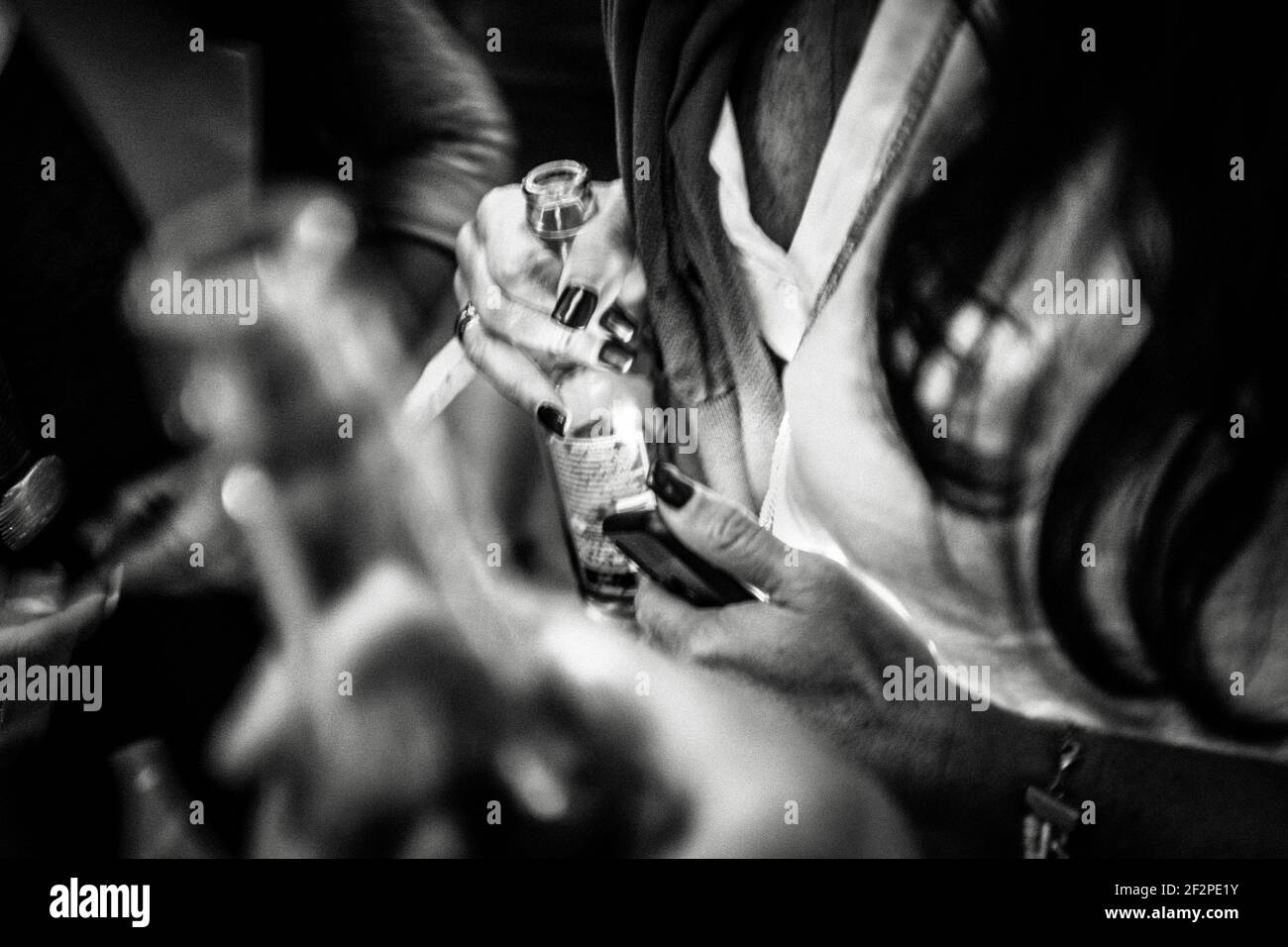 Deutschland, Bayern, Antdorf, Festwoche des Trachtenvereins. Frau mit dunklen Fingernägeln hält ihr Smartphone und eine Bierflasche. Stockfoto