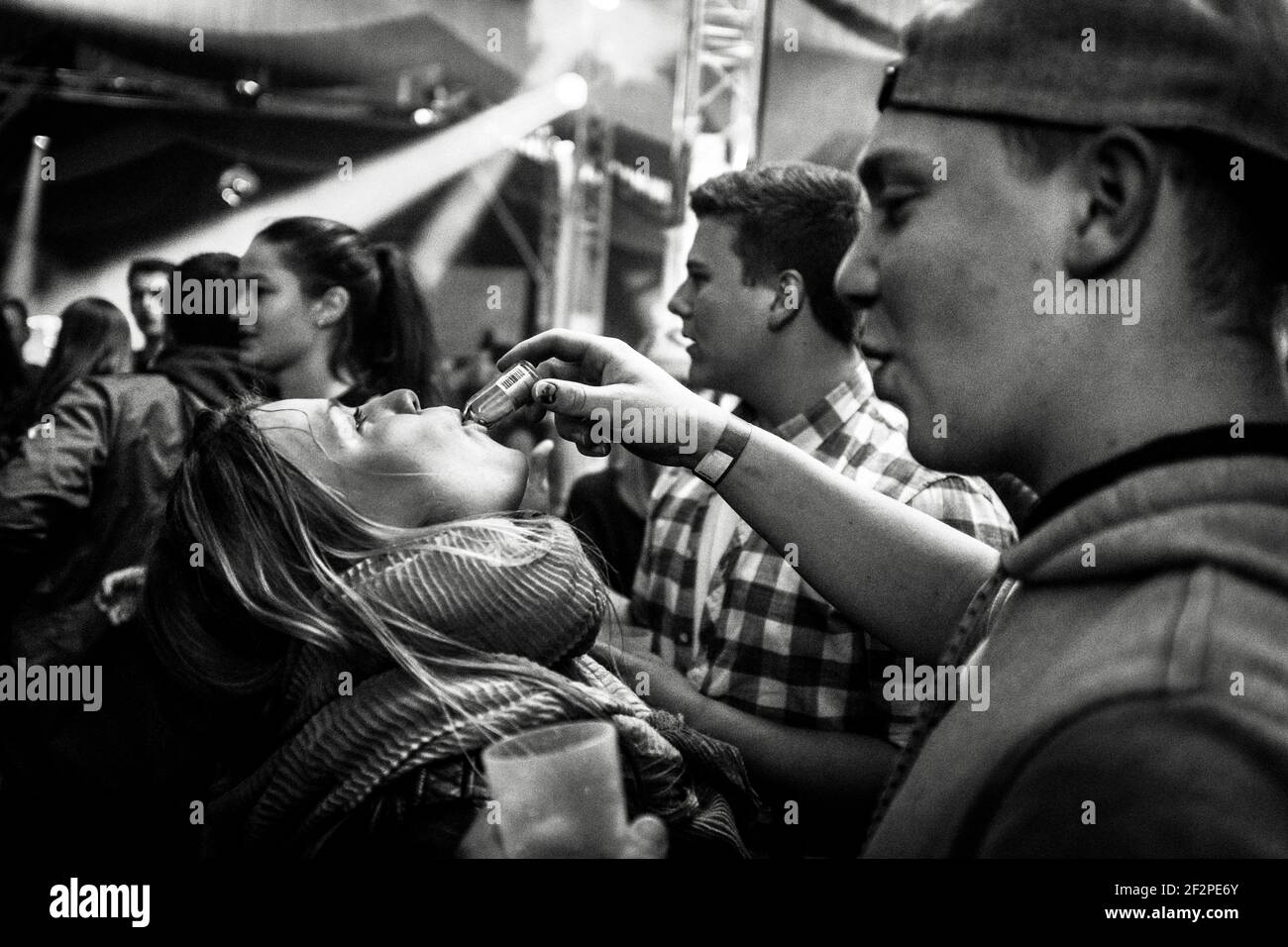 Deutschland, Bayern, Antdorf, Festwoche des Trachtenvereins. Während der Party im Festzelt gibt ein junger Mann einer jungen Frau Brandy aus einer Flasche zu trinken. Stockfoto