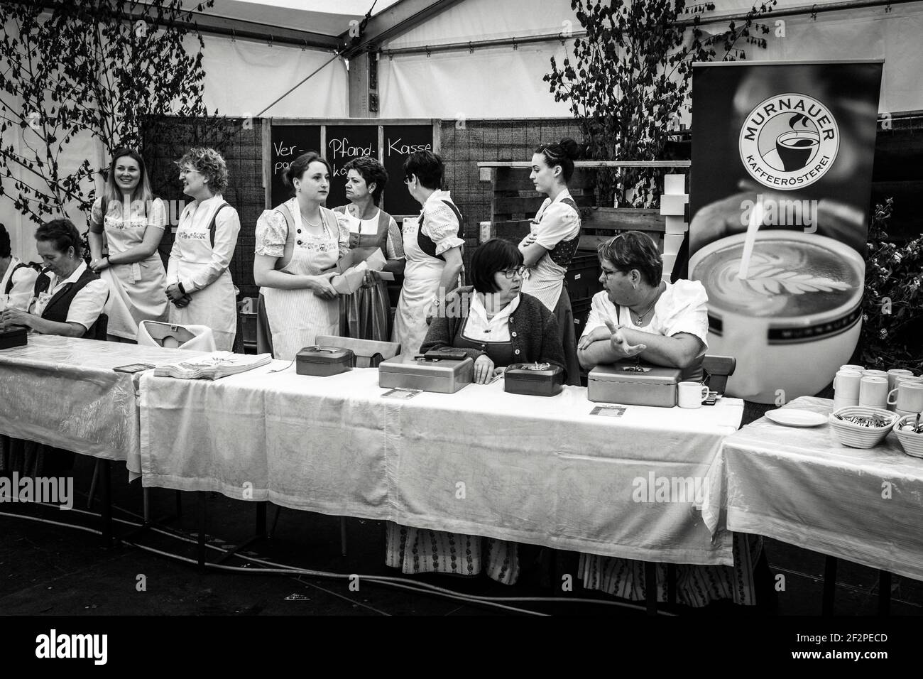Deutschland, Bayern, Antdorf, Festwoche des Trachtenvereins. Frauen in Kostüm am Tisch mit Geldkassetten, um Quittungen auszustellen. Stockfoto