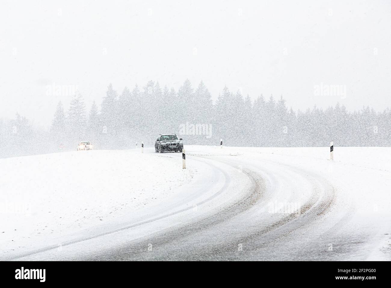 Deutschland, Bayern, Auto auf schneebedeckter Landstraße mit Reifenspuren. Stockfoto
