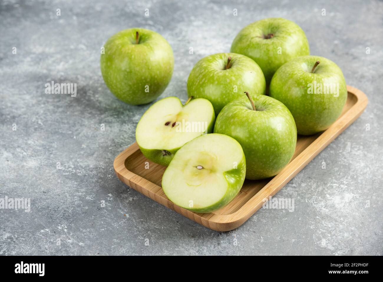 Bündel von ganzen und in Scheiben geschnittenen grünen Äpfeln auf Holzplatte Stockfoto