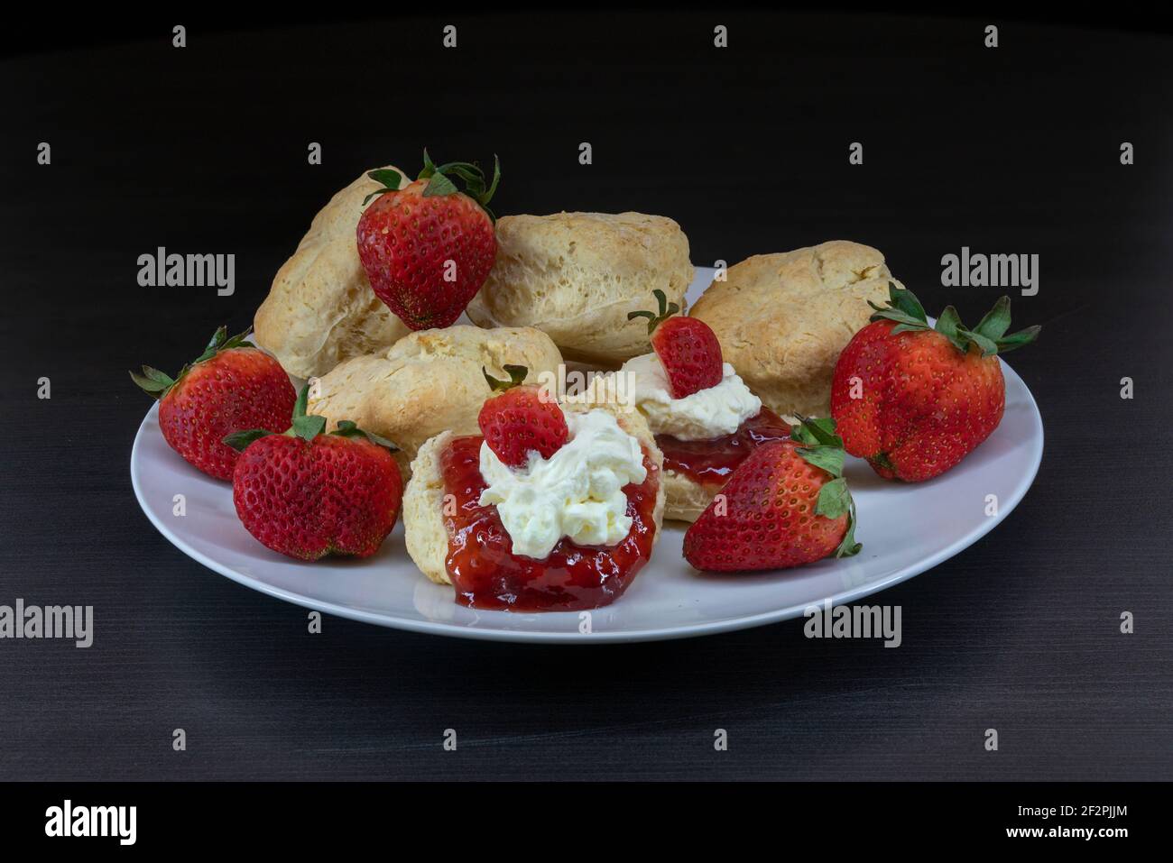 Ein Teller mit frischen Scones mit Sahne, Marmelade und Erdbeeren Stockfoto