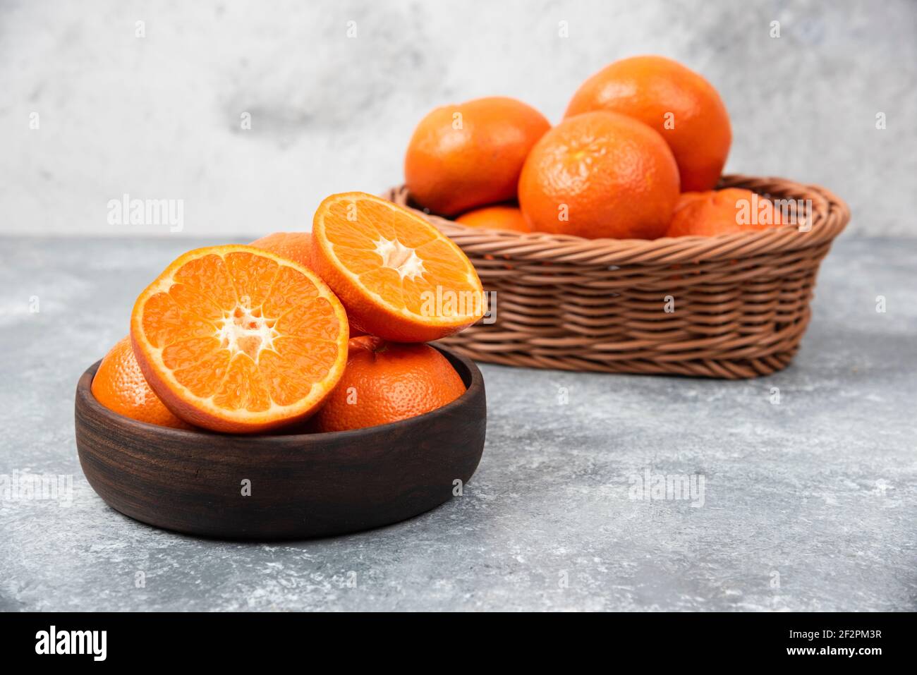 Eine Holzschale voller saftiger Orangenfrüchte auf Stein Hintergrund Stockfoto