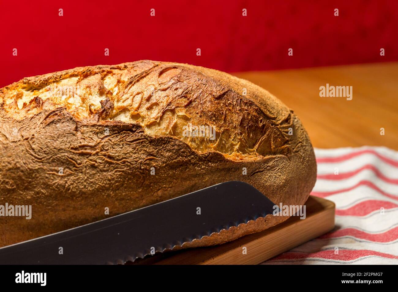 Frisches hausgemachtes Bio-Brot mit Brotmesser auf Holzplatte Stockfoto