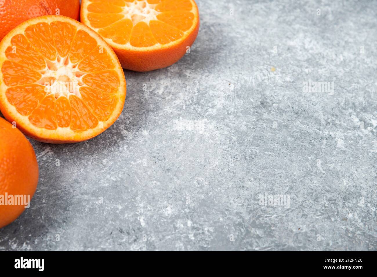 Ganze und schneiden saftige frische Orangenfrüchte auf ein gelegt Steinhintergrund Stockfoto