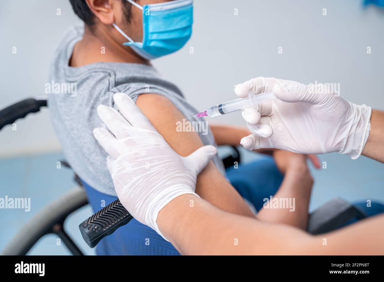 Arzt, der eine Impfung in der Schulter des Patienten behinderten Person, Grippe-Impfung Injektion am Arm, Coronavirus, covid-19 Impfstoff Krankheit vorbereiten Stockfoto
