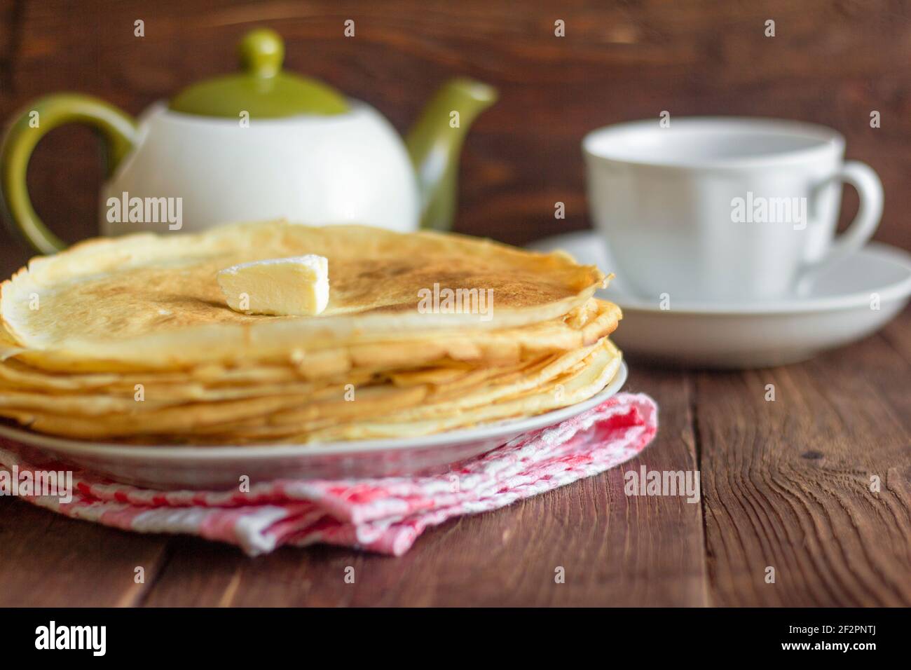 Hausgemachte gebackene Pfannkuchen und Teegeschirr auf einem dunklen Holztisch. Stockfoto