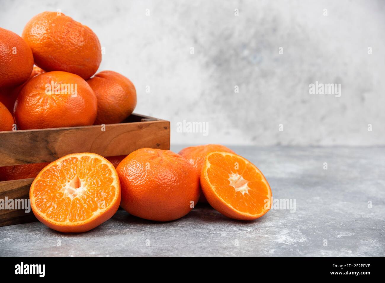Eine alte Holzkiste voller saftiger Orangenfrüchte Steinhintergrund Stockfoto