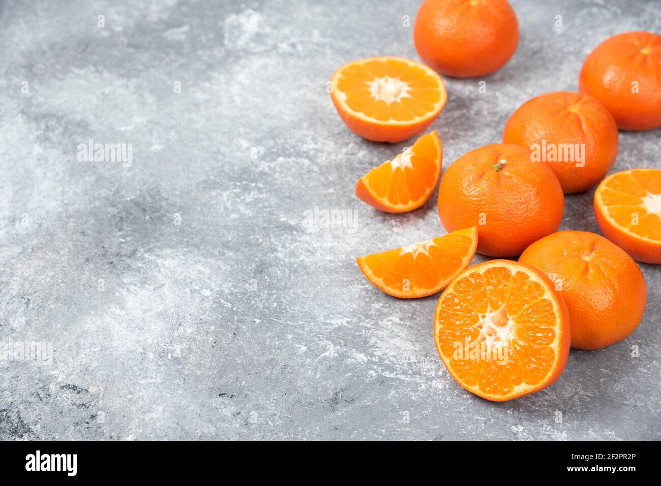 Ganze und schneiden saftige frische Orangenfrüchte auf ein gelegt Steinhintergrund Stockfoto