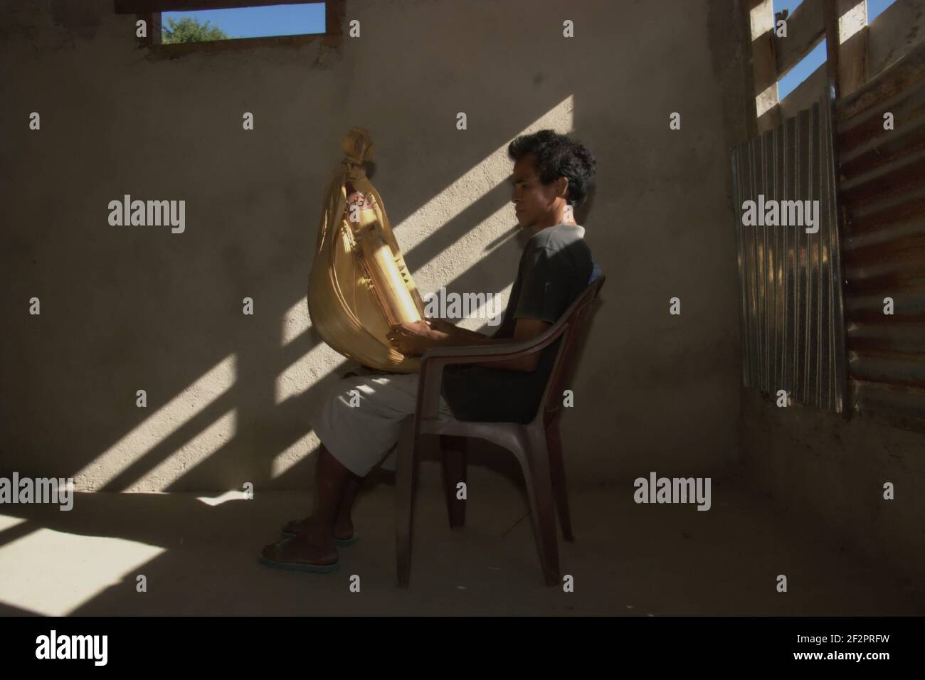 Hance Pah posiert für ein Foto mit einem elektrischen Sasando, dem traditionellen Saiteninstrument der Roten Insel, das er in seinem Haus im Dorf Lalu Koen, Rote Insel, East Nusa Tenggara, Indonesien, schuf. Stockfoto