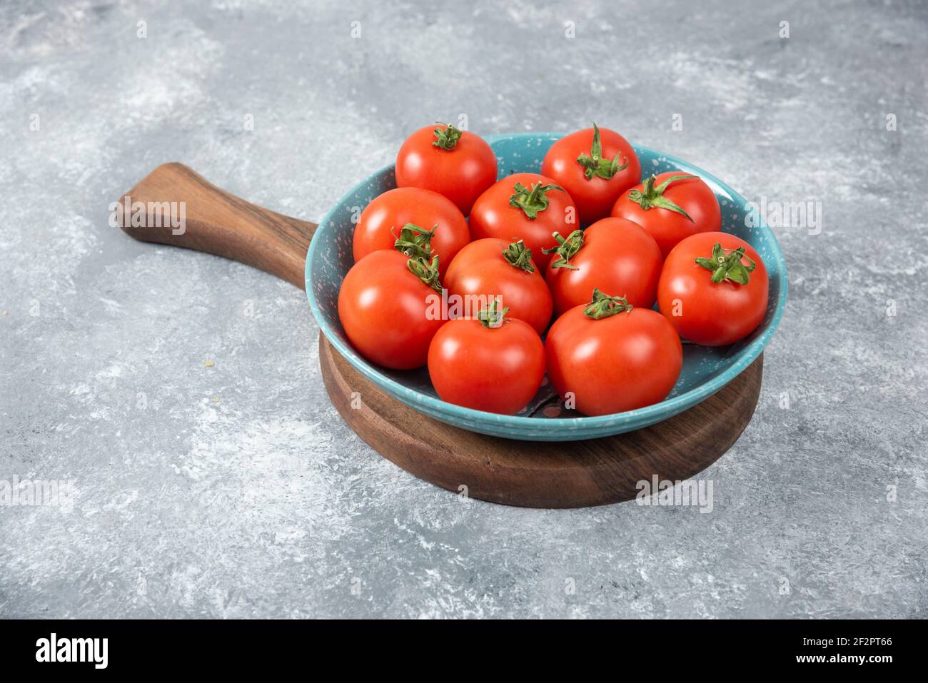 Blaue Schüssel voll von roten frischen Tomaten auf Marmor Hintergrund Stockfoto