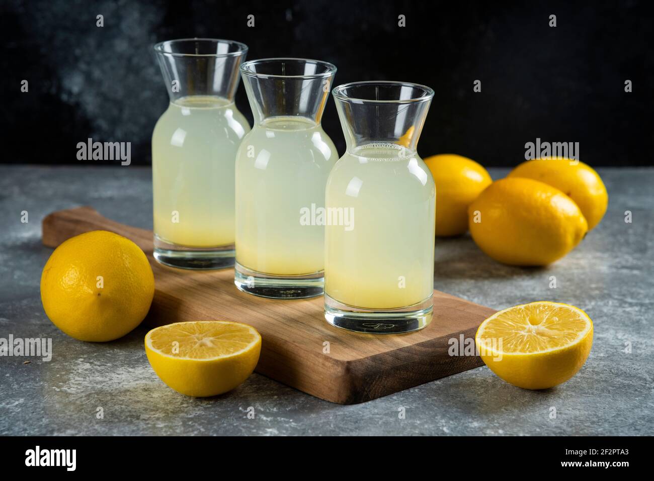 Drei Glaskrüge mit leckerer Limonade auf einem Holzbrett Stockfoto