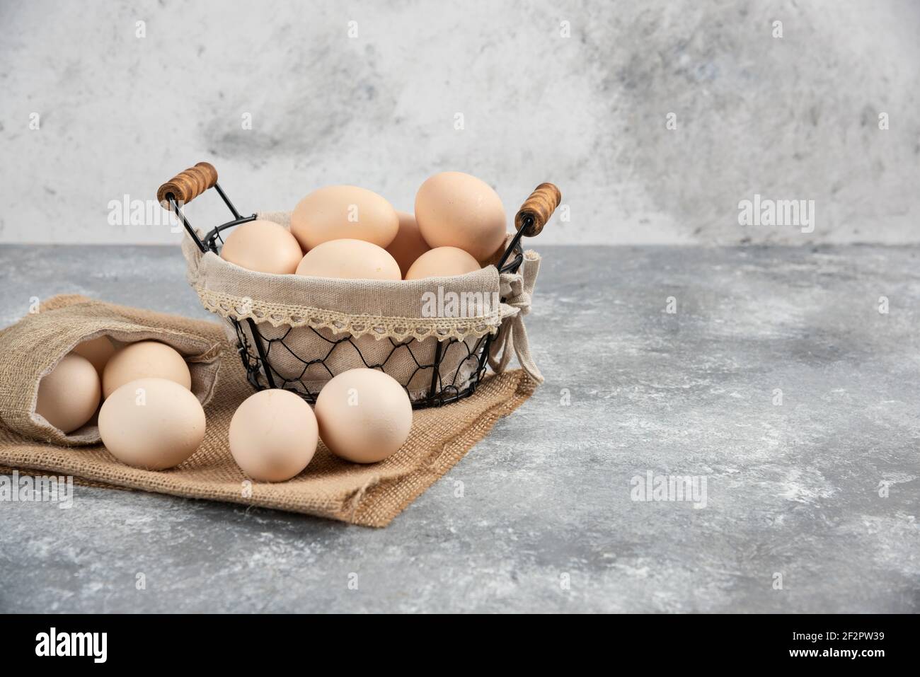 Korb und Sacktuch aus Bio-frischen ungekochten Eiern auf Marmor Oberfläche Stockfoto