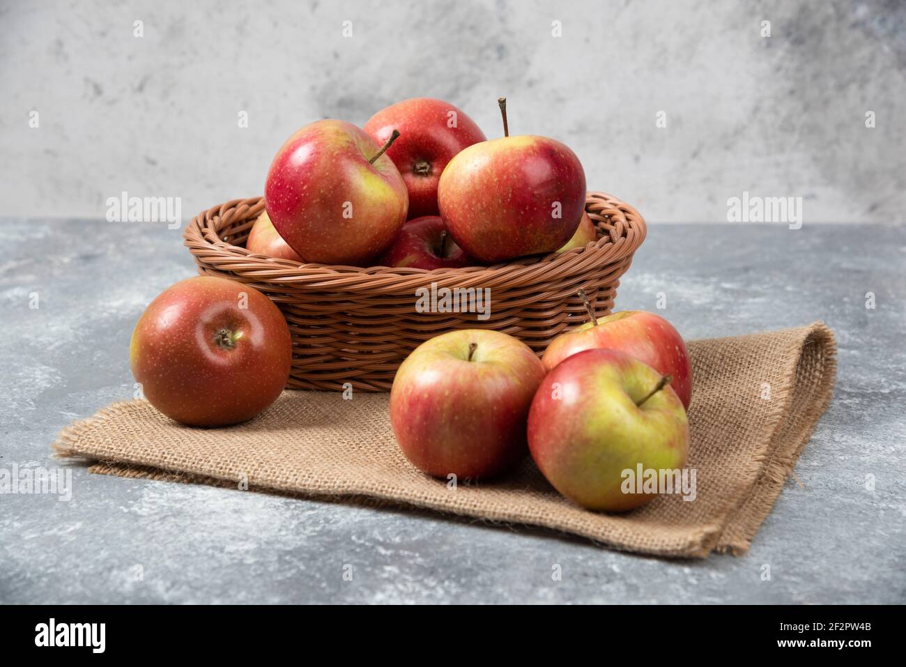 Korbkorb mit reifen glänzenden Äpfeln auf Marmoroberfläche Stockfoto
