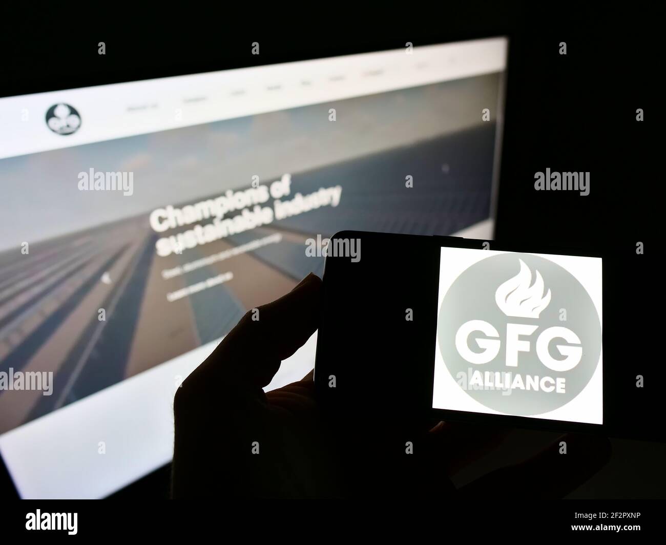 Person mit Smartphone mit Firmenlogo der Gupta Family Group Alliance (GFG Alliance) auf dem Bildschirm vor der Webseite. Fokus auf Handy-Display. Stockfoto
