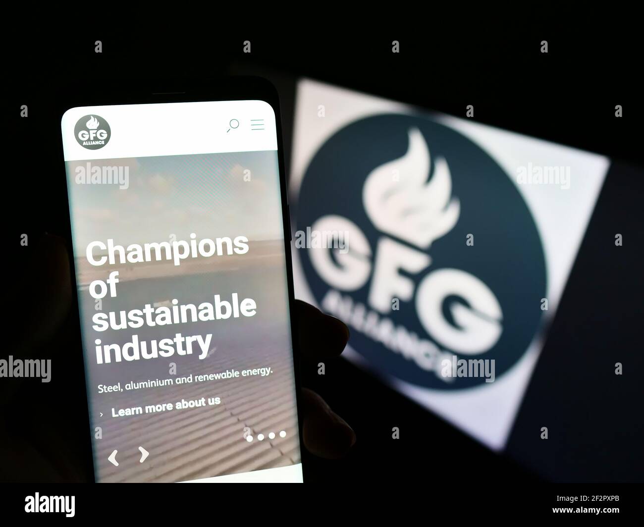 Person mit Mobiltelefon und Webseite der Gupta Family Group Alliance (GFG Alliance) auf dem Bildschirm vor dem Logo. Fokus auf der Mitte des Telefondisplays. Stockfoto