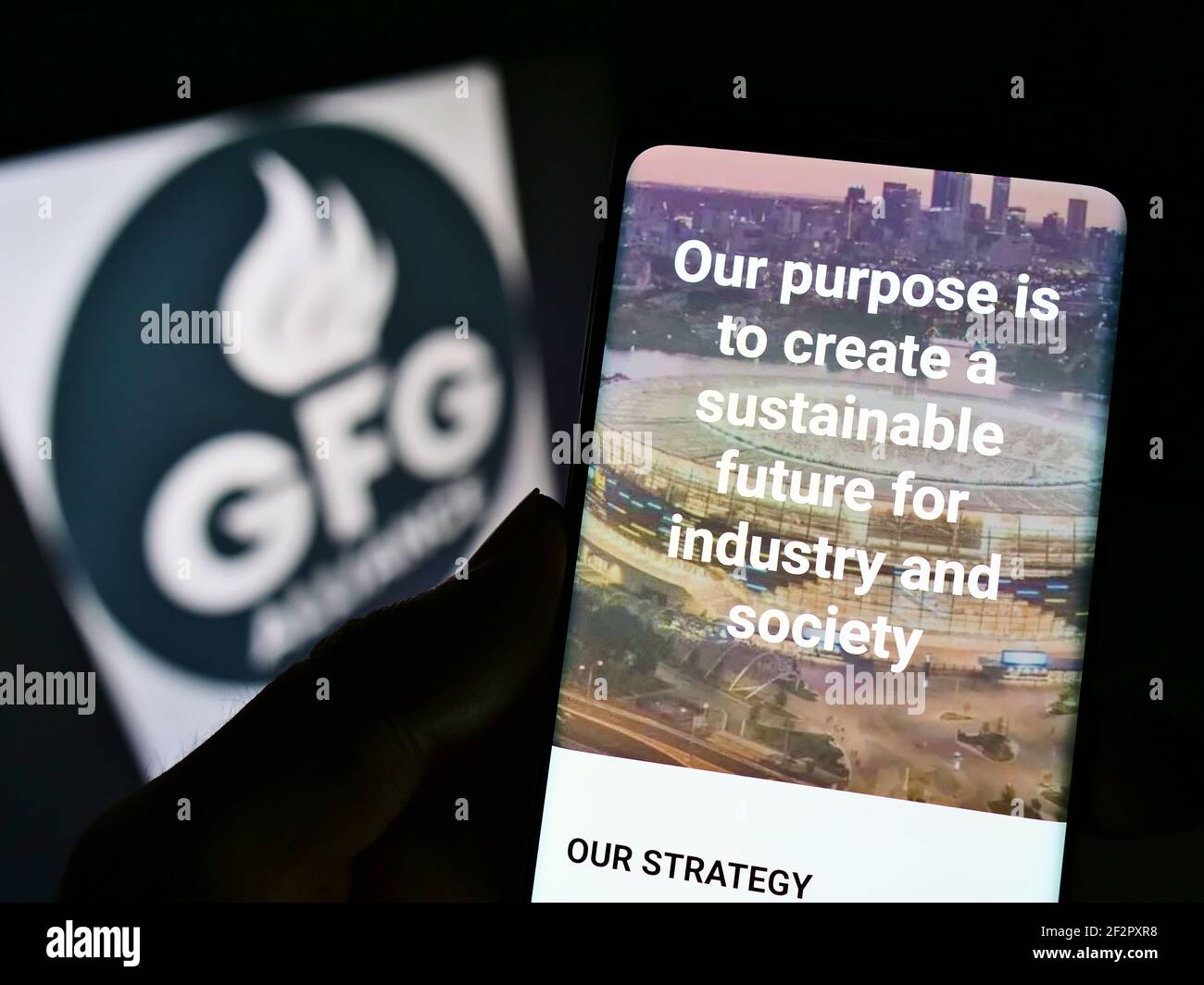 Person mit Mobiltelefon und Webseite der Gupta Family Group Alliance (GFG Alliance) auf dem Bildschirm vor dem Logo. Fokus auf der Mitte des Telefondisplays. Stockfoto