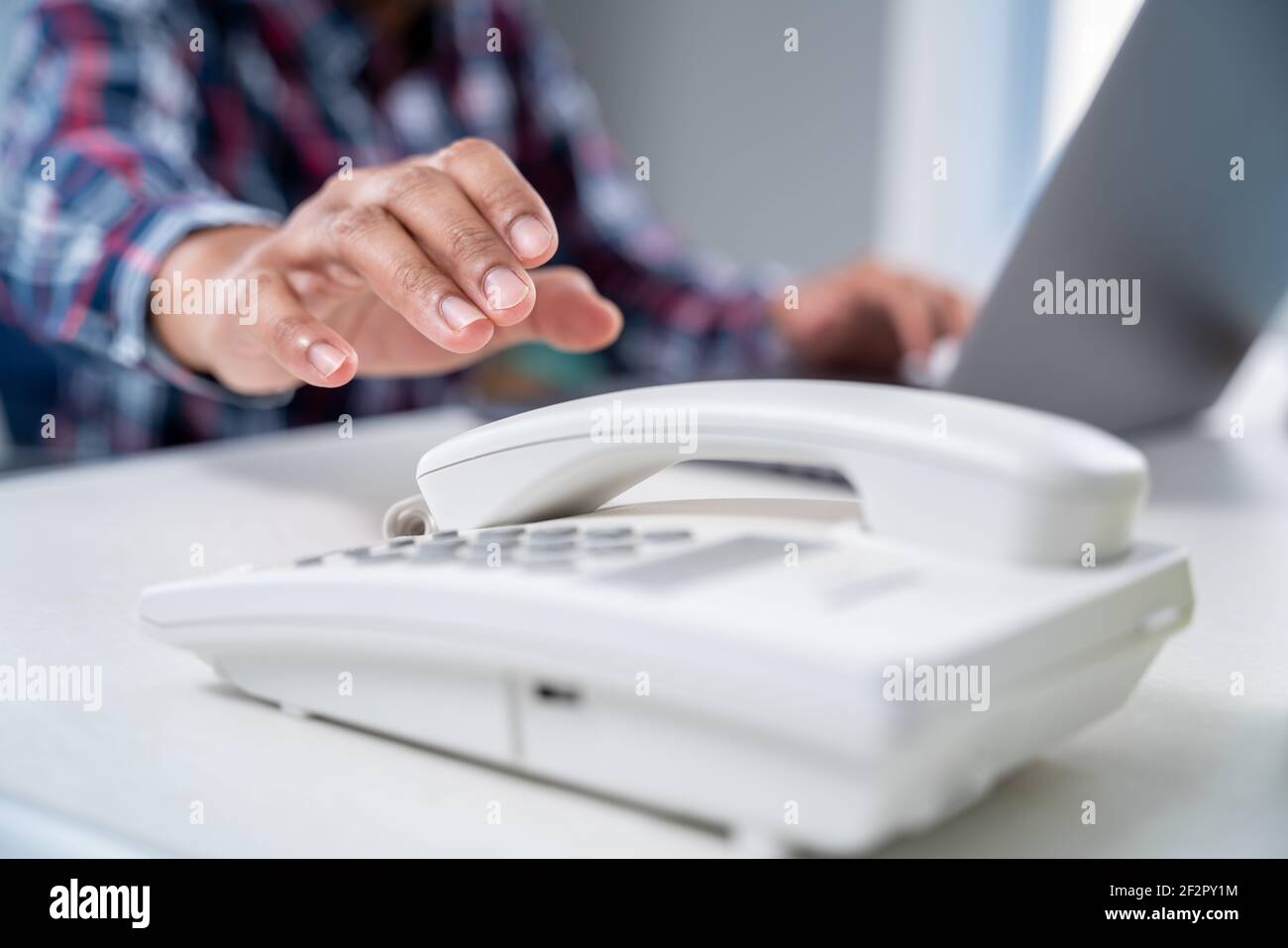 Nahaufnahme Hand des Geschäftsmannes nimmt den Telefonhörer im Büro. Stockfoto