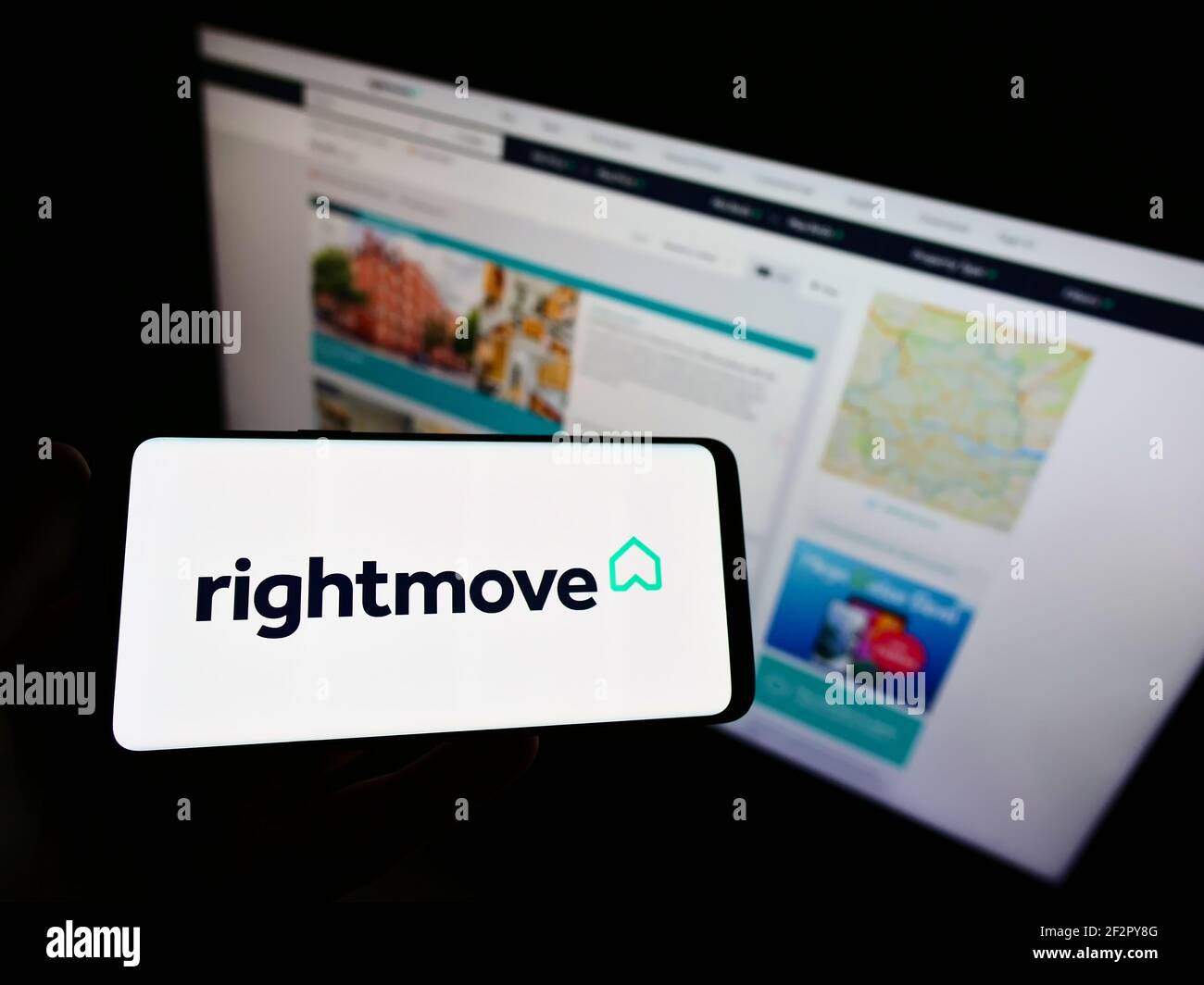 Person, die Smartphone mit Logo des britischen Immobilien-Online-Portals Rightmove plc auf dem Bildschirm vor der Website hält. Konzentrieren Sie sich auf die Telefonanzeige. Stockfoto Person, die Smartphone mit Logo des britischen Immobilien-Online-Portals Rightmove plc auf dem Bildschirm vor der Website hält. Konzentrieren Sie sich auf die Telefonanzeige. Stockfoto
