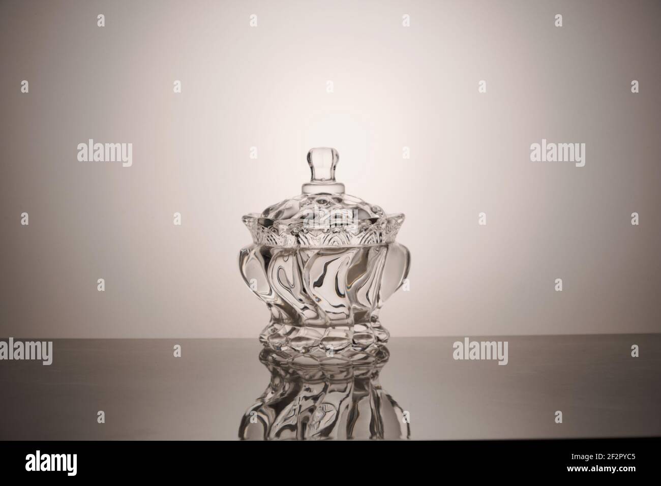 Leere Glasschüssel mit Deckel und Spiegelung Ein grauer Hintergrund Stockfoto