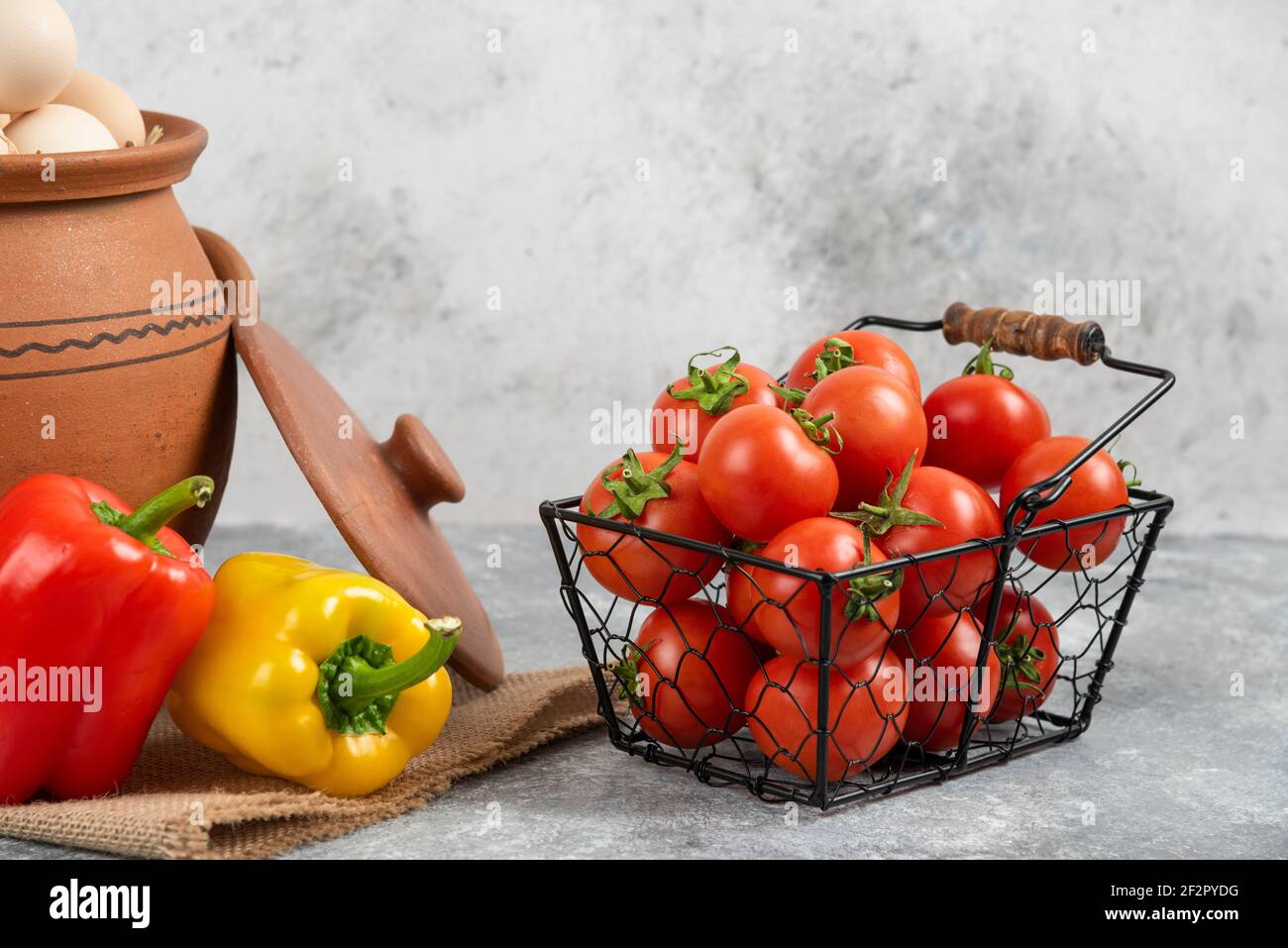 Topf mit rohen Eiern, Tomaten und Paprika auf Marmor Hintergrund Stockfoto